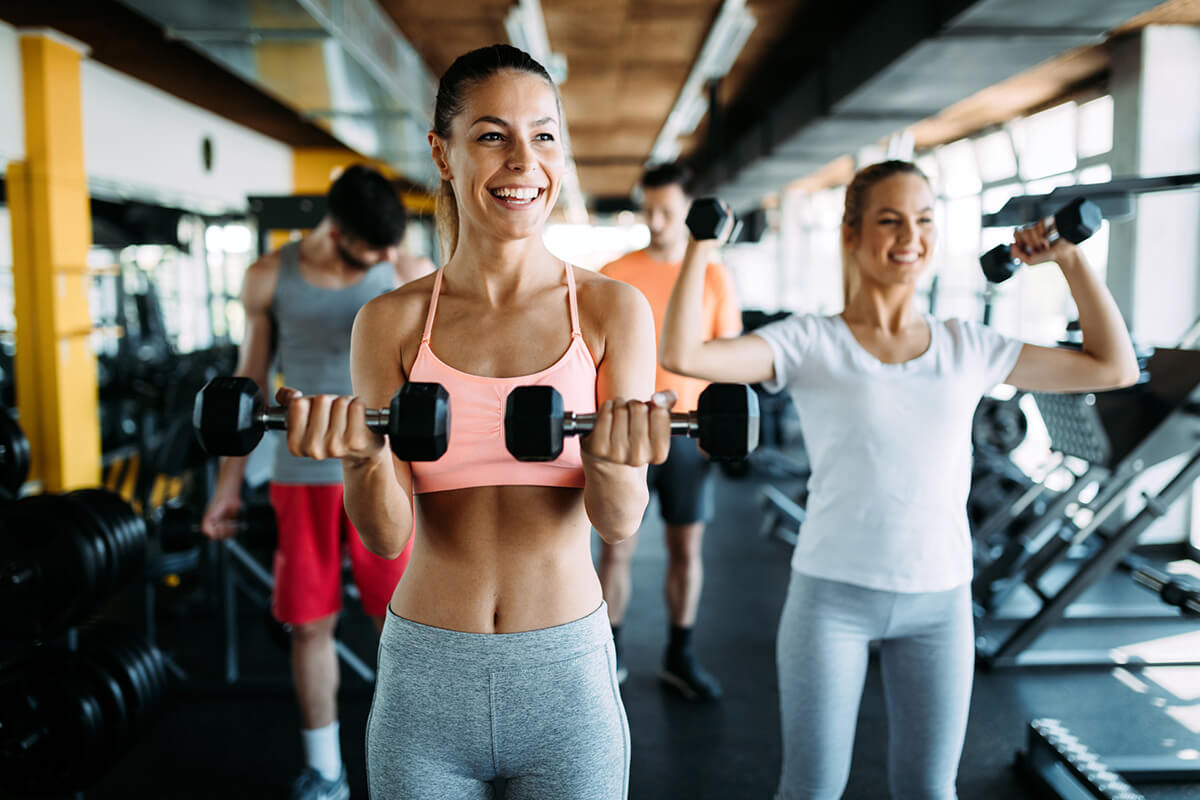 Pessoas treinando com halteres em uma academia